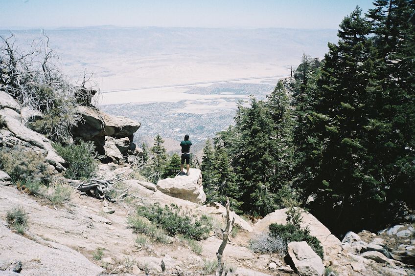 Man at the edge of a cliff photographing the valley